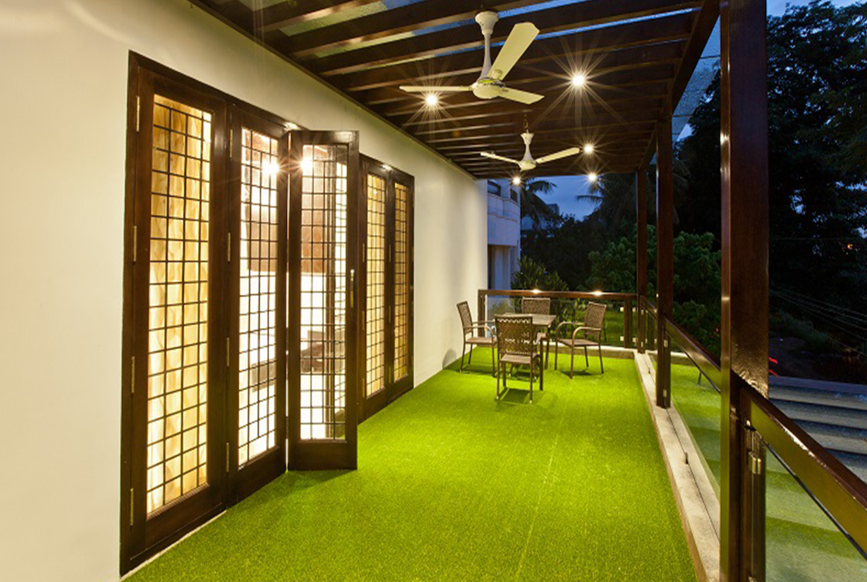 Modern outdoor balcony with artificial grass flooring, wooden panel
						 ceiling, and seating arrangement