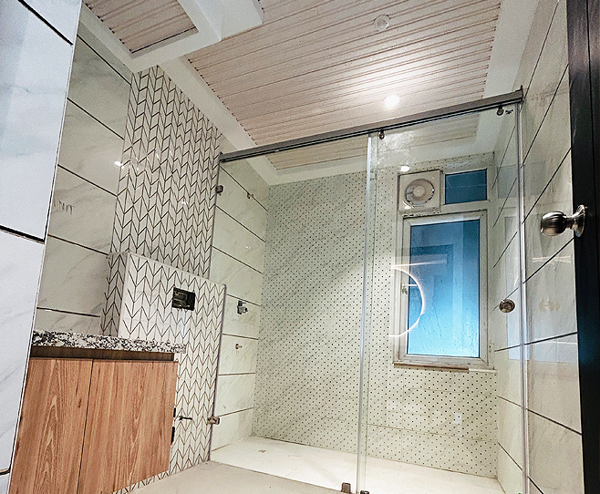 Modern bathroom with glass shower enclosure, patterned
								 wall tiles, and wood vanity under soft ceiling lights.