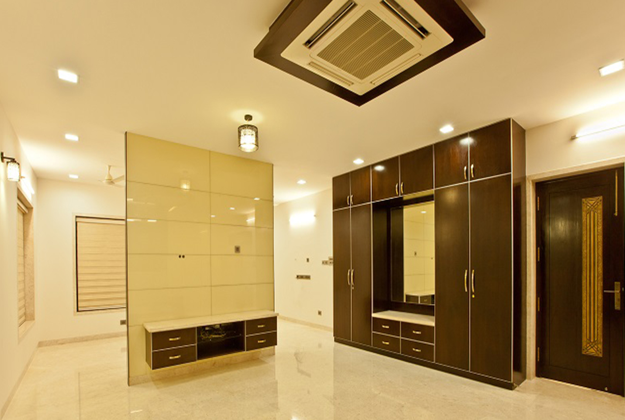 Spacious bedroom with built-in dark wood wardrobe, beige wall
						 paneling, and ambient ceiling lighting