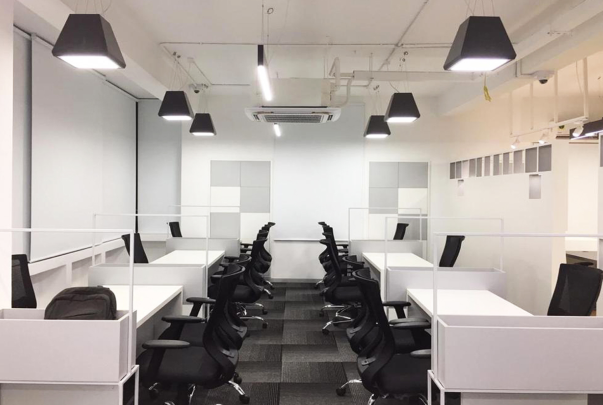 Modern office interior with black ergonomic chairs,
						 white desk partitions, and overhead lighting