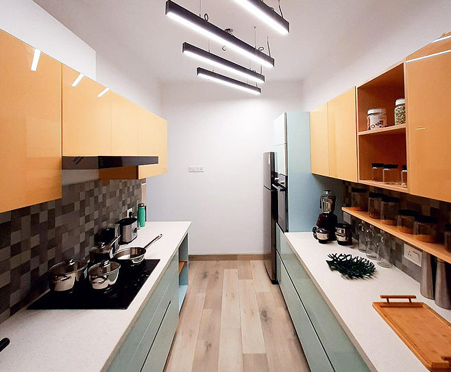 Compact kitchen featuring orange and blue dual-tone
								 cabinets, white countertops, and stylish pendant lighting.