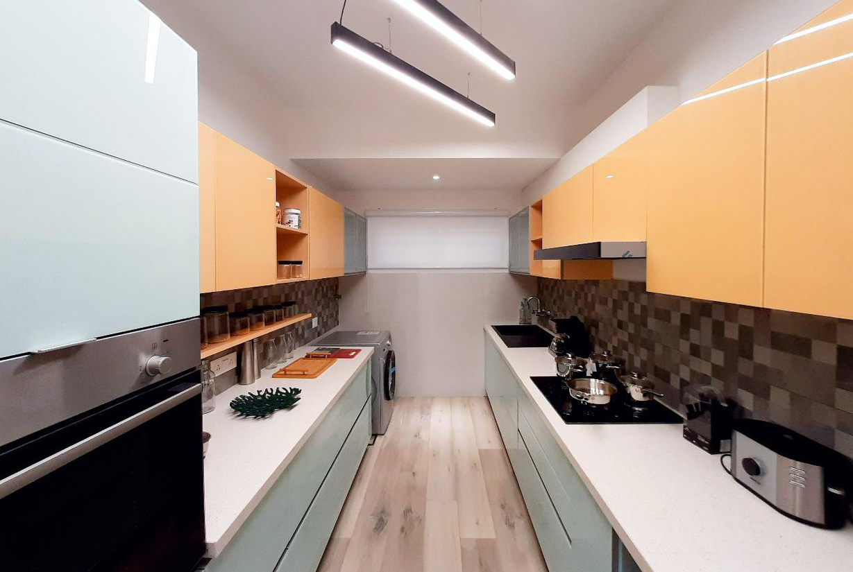 Modern kitchen with pastel blue and orange dual-tone cabinets,
						 sleek countertops, and overhead linear lights.