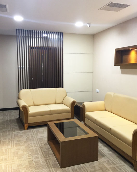 Waiting room with beige sofas,
								 wooden coffee table, wall-mounted shelves, cozy seating area